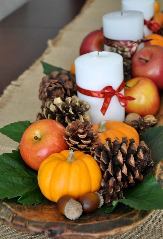 a natural fall centerpiece of a dough bowl, foliage, pinecones, nuts, acorns, apples, pumpkins and candles