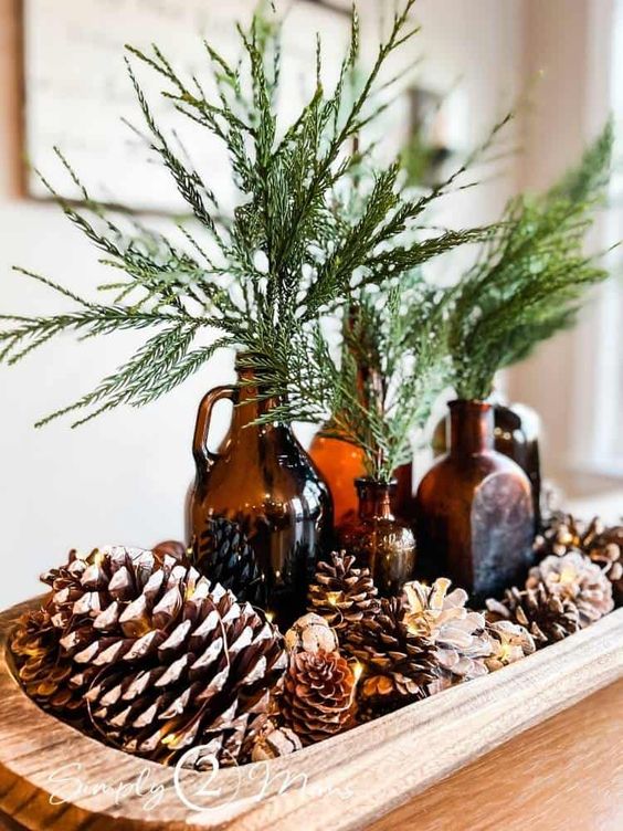 a natural fall or winter centerpiece of a bread bowl, pinecones, acorns, apothecary glass bottles and greenery