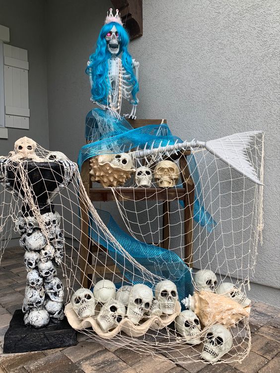 a tropical to mermaid outdoor Halloween decoration of a skeleton mermaid, a fishnet and skulls can be placed on your porch