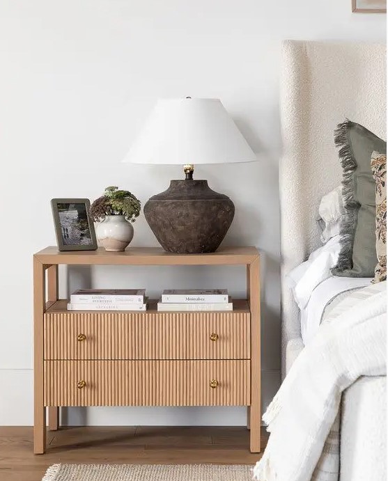 a large oak fluted nightstand with coffee books, a table lamp, potted plants is a trendy and edgy idea for a bedroom
