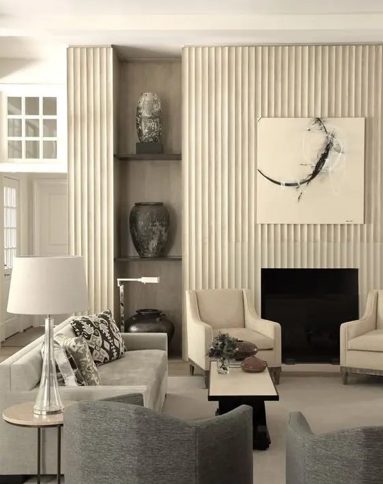 a refined living room with a fireplace and a reeded surround, built-in shelves, neutral and graphite grey furniture, coffee tables