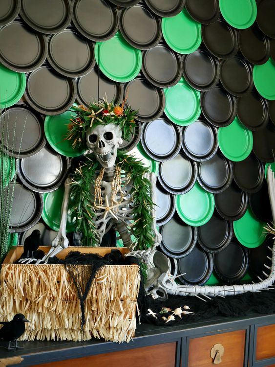 indoor Halloween decor with black and green plastic dishes, a mermaid skeleton in a necklace and a chest with stuff