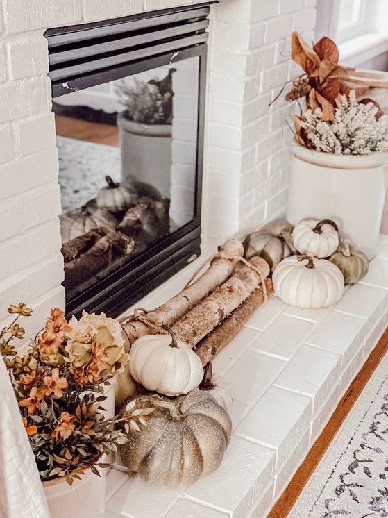 a lovely neutral rustic fireplace with firewood, heirloom pumpkins, dried blooms and leaves in buckets is a cool idea