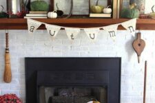20 a lovely rustic fall mantel with bold pumpkins, a wreath with berries, a candle lantern, branches in planters and books is all cool