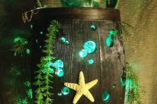 21 a barrel with turquoise detailing, greenery, a prate skeleton inside and some lights