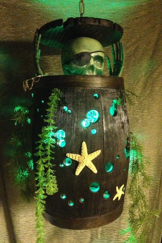 a barrel with turquoise detailing, greenery, a prate skeleton inside and some lights