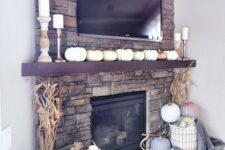 21 a lovely rustic fall mantel with lots of faux pumpkins, corn husks, pillar candles, a basket with pumpkins and blankets