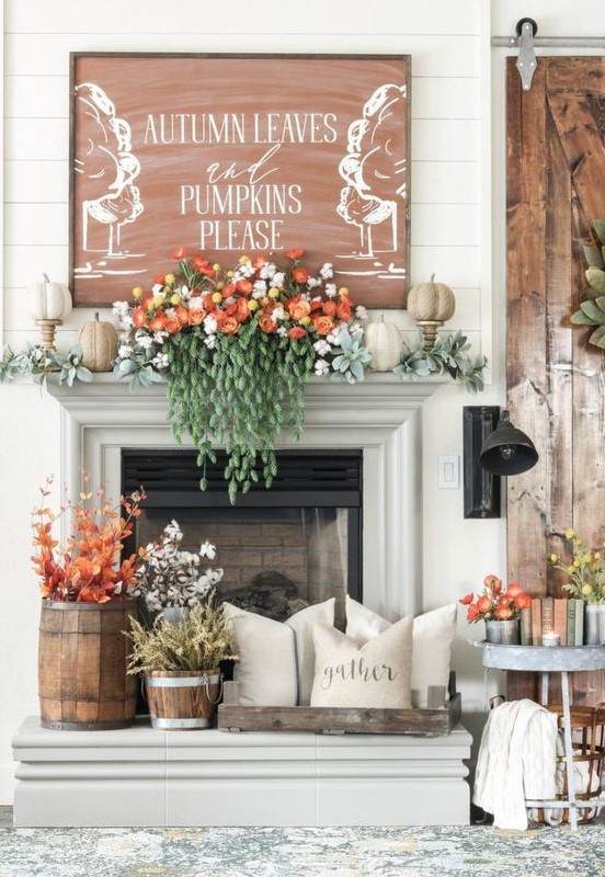a lush fall mantel with pale greenery, faux pumpkins, gorgeous florals and cascading greenery, fall leaves and cotton in buckets and a fall sign