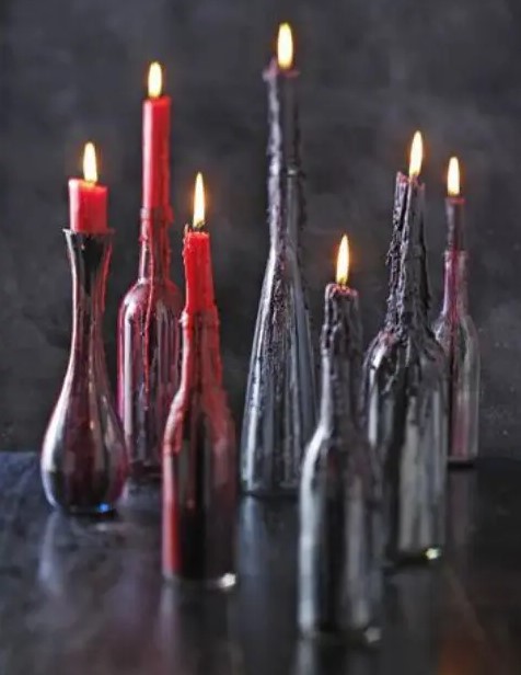 bottles with candle of several shade sof blood look like it is dripping down the bottles
