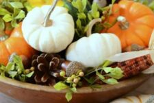 23 a stylish harvest-inspired centerpiece of a wooden bowl, foliage, corns and acorns,pinecones and various pumpkins