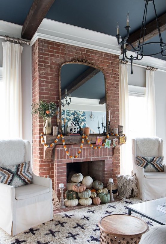 a natural pumpkin stack in the fireplace decorated with fall colored garlanfs and greenery
