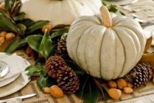 24 a stylish Thanksgiving centerpiece of pinecones, nuts, foliage and oversized neutral pumpkins stacked