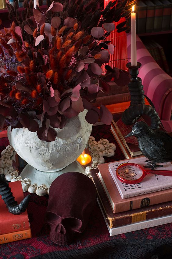 exquisite vampire Halloween decor with a burgundy velvet skull, burgundy and red dried foliage and a blackbird