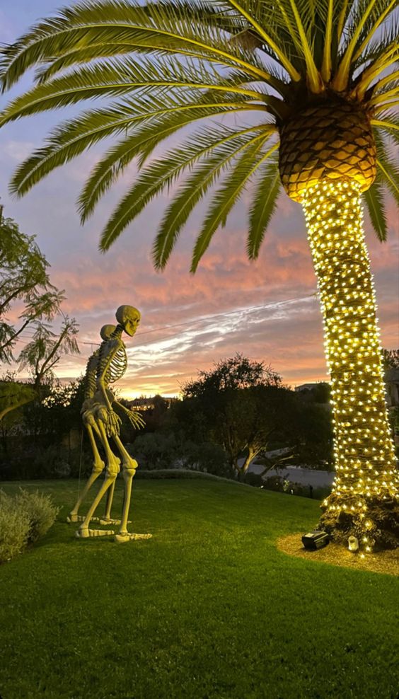 tropical Halloween decor with a lit up palm tree and a couple of skeletons is a cool solution for your backyard