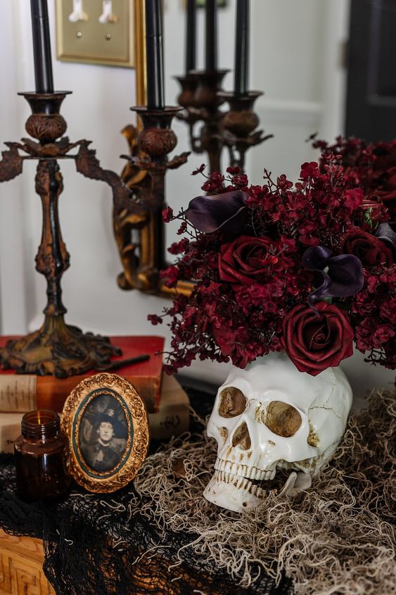 refined Halloween vampire decor with a skull, deep purple callas and red roses, a witch portrait and vintage candelholders