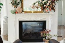 27 a pretty and bold fall mantel with bright and pastel pumpkins, a mirror in an ornated frame, bold leaves and blooms is a very chic idea