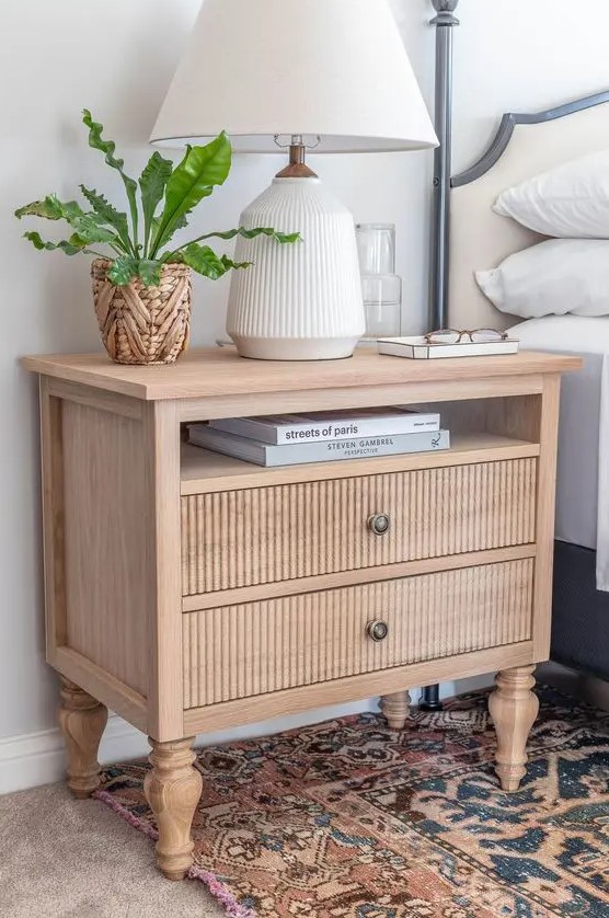 a stained vintage nightstand with fluted drawers, elegant legs, a fluted table lamp and a potted plant is amazing