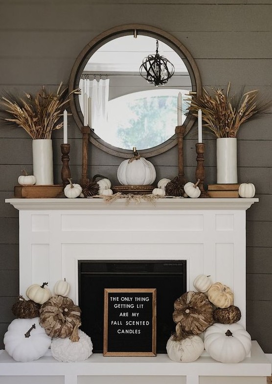 a rustic fall fireplace with a sign, white and vine pumpkins, wheat and grasses in vases, candles and pumpkins on the mantel