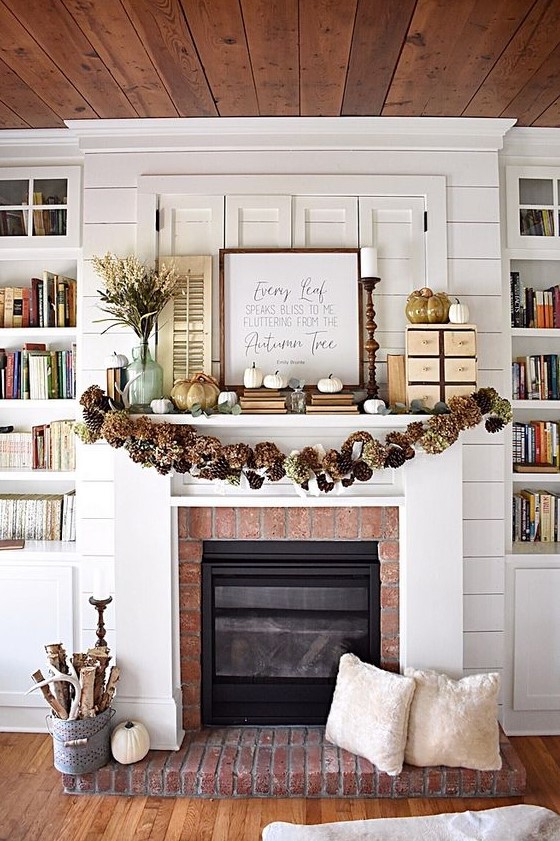 a rustic fall mantel with a pinecone and hydrangea garland, white pumpkins and faux porcelain ones, a branch arrangement in a bucket