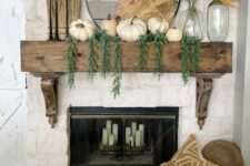 31 a rustic fall mantel with cascading greenery, white pumpkins, a wooden cutting board, pampas grass, black candlesticks with candles