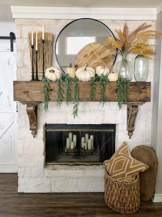 a rustic fall mantel with cascading greenery, white pumpkins, a wooden cutting board, pampas grass, black candlesticks with candles