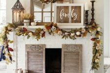 32 a rustic fall mantel with dried fall leaves and pumpkins, candles in wooden candle holders, wheat arrangements and a rustic sign
