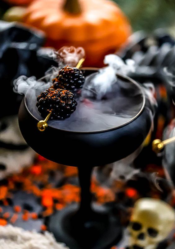 a matte black glass with a smoky cocktail and blackberries is a gorgeous idea for a vampire Halloween party
