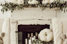 33 a shabby chic and rustic fall mantel with greenery, white pumpkins, a lush wreath with greenery and candles in the fireplace