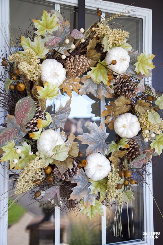 a fall wreath of pinecones, leaves, pumpkins, nuts and other stuff is a beautiful fall decoration with a lot of natural touches