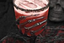 34 a red Halloween cocktail in a spectacular skeleton hand glass with black rim is a stunning idea for a vampire party