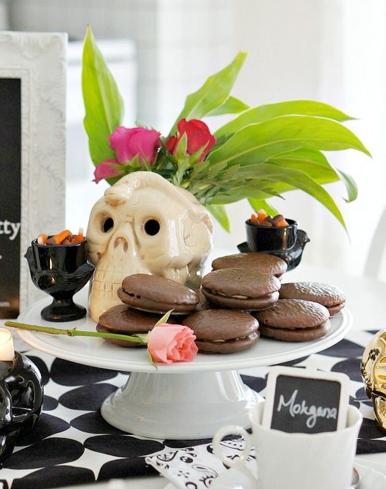 tropical Halloween with chocolate pies, fresh fruit, greenery and blooms in a skull vase