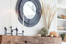 36 a stylish rustic fall mantel with a black candelabra with tall candles, natural heirloom pumpkins and wheat in a vase plus a mirror in a cool black frame