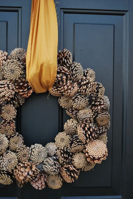 a simple and cool fall to winter wreath of pinecones, with a gold ribbon, is a stylish decoration to make