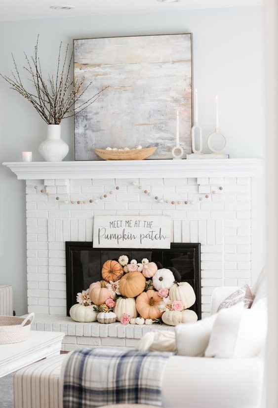 a white brick fireplace with white and pastel pumpkins, blooms, a garland and some branches on the mantel is great for the fall