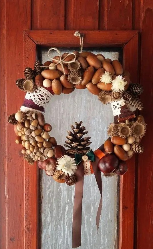 an eye catchy fall to winter wreath of acorns, nuts, pinecones, dried blooms, lace, ribbon and a twine bow is a cool idea