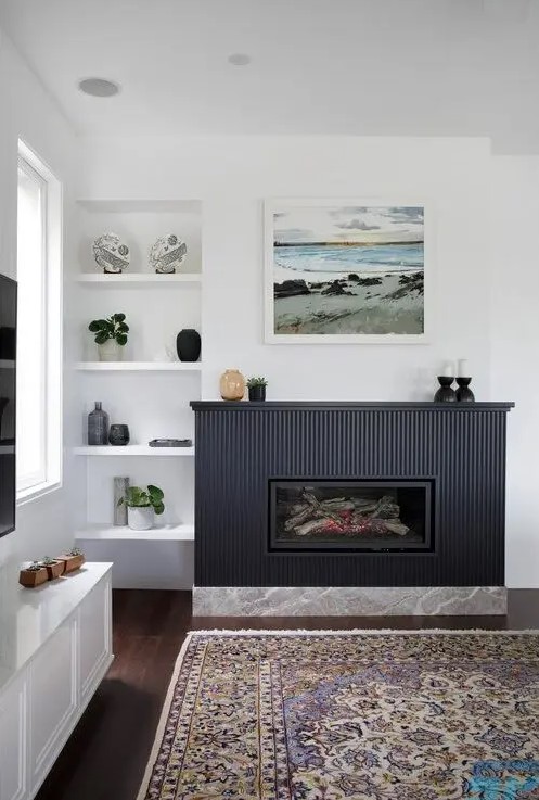 a modern living room with a fireplace with a navy reeded surround, built-in niche shelves and a bold printed rug