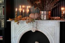 41 an elegant and refined fall mantel with firewood, pillar candles, faux leaves, a pumpkin and a dried leaf arrangement