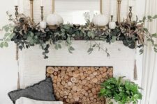 42 an elegant rustic fall mantel with greenery, white pumpkins, brass candlesticks and a mirror, a wood slice screen in the fireplace is chic