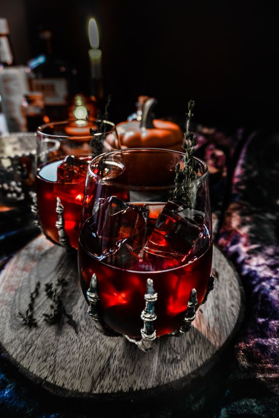 pomegranate bourbon cocktail in a skeleton hand glass is a gorgeous idea for Halloween