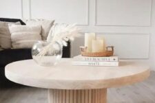 45 a beautiful coffee table with a fluted base and an oval stone tabletop, with decor and books is amazing