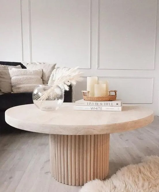 a beautiful coffee table with a fluted base and an oval stone tabletop, with decor and books is amazing