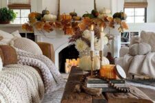 45 fall living room styling with pumpkins and large leaves on the mantel, a reclaimed wood coffee table with a pumpkin and candles