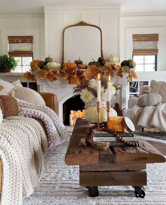 fall living room styling with pumpkins and large leaves on the mantel, a reclaimed wood coffee table with a pumpkin and candles