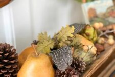 47 a mantel decorated with pinecones, pears, leaves, feathers and berries is a lovely idea for rustic fall styling