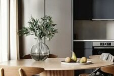 48 a black kitchen, a round table with a fluted base, light-stained chairs, greenery in a vase are a chic and modern combo
