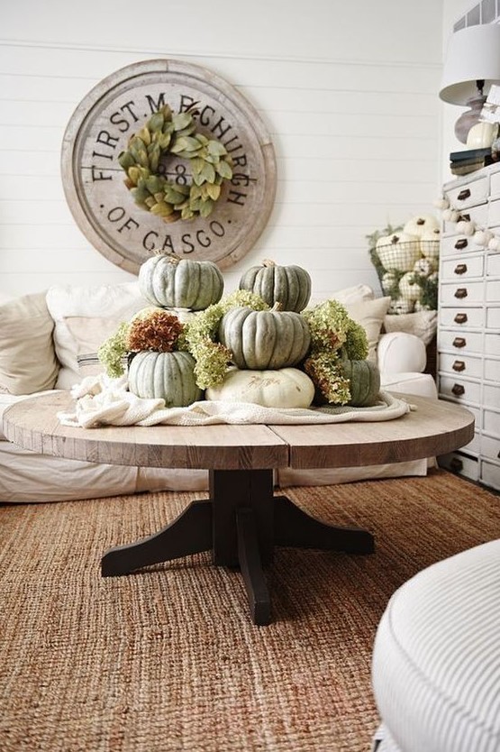 white fabric and large heirloom pumpkins plus green hydrangeas stacked on it for a famrhouse living room