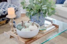 50 a bowl with neutral fabric pumpkins and a blue pot with greenery plus a candle in a wooden candleholder