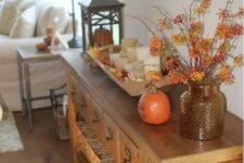 51 a console table with a fall leaf arrangement, a pumpkin and a wooden bowl with leaves and candles for the fall