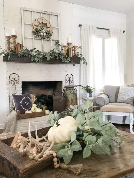 a dough bowl with a rosary, antlers, greenery and a white pumpkin for farmhouse coffee table decor