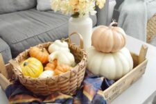 57 a tray with a checked napkin, a basket with faux gourds and pumpkins, a stack of pumpkins and a white vase with fall blooms